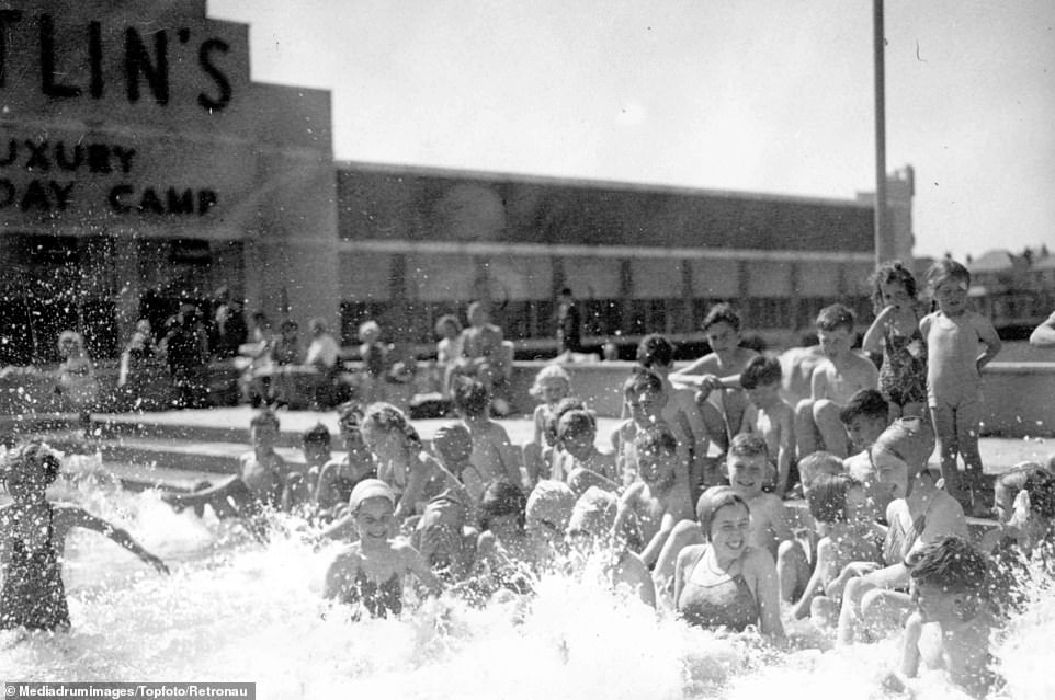 Holidaymakers play and splash around in the water in an outdoor pool at the holiday camp in Clacton-on-Sea, Essex, in 1948. The Butlin's 'Luxury Holiday Camp' signage can also be made out in the background
